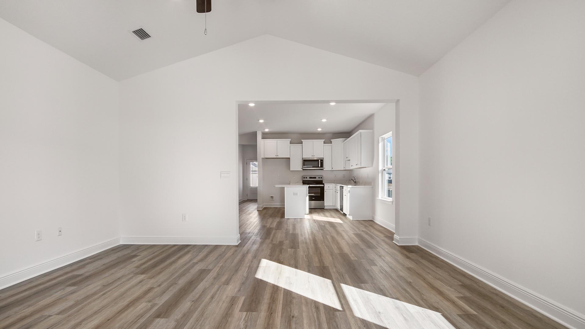 Living room with EVP flooring and a ceiling fan and door to primary bedroom.