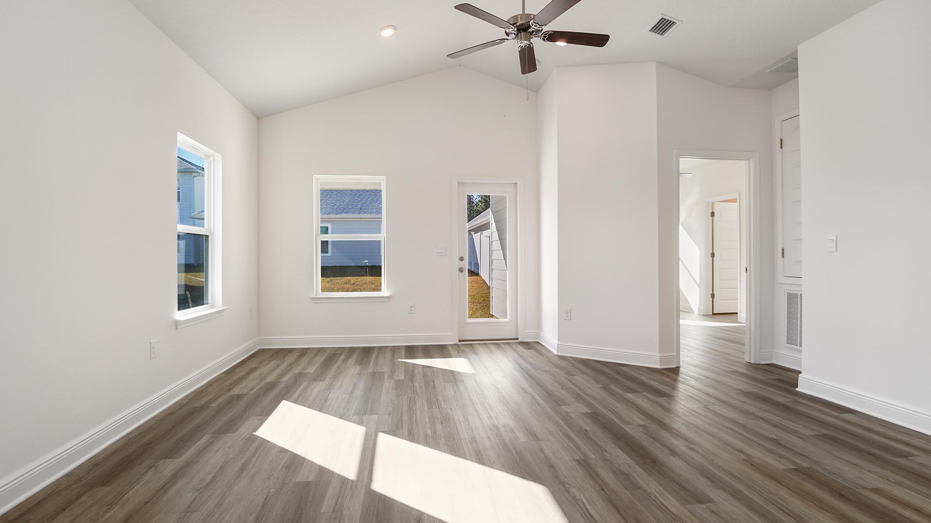 Living room with vaulted ceilings and window and glass back door to covered back patio.