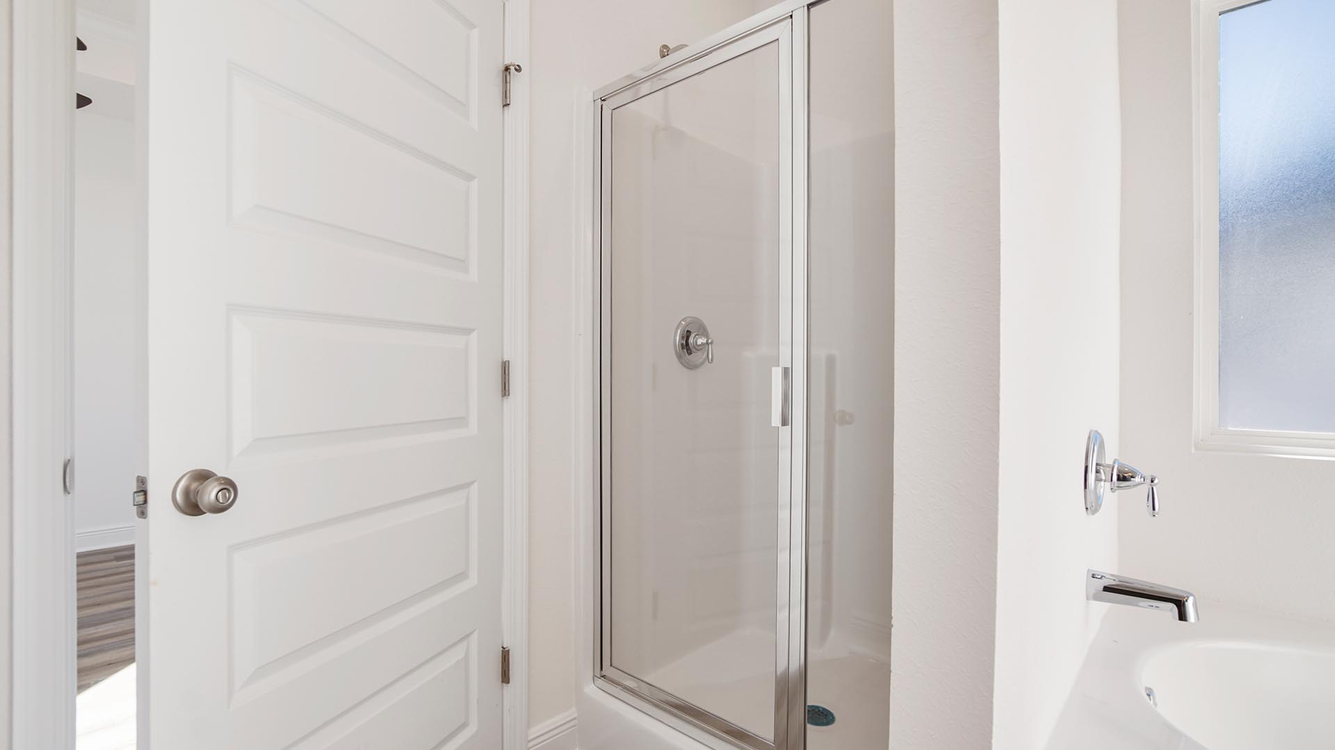 Primary bathroom with large soaking tub below a frosted glass window and a separate standing shower.