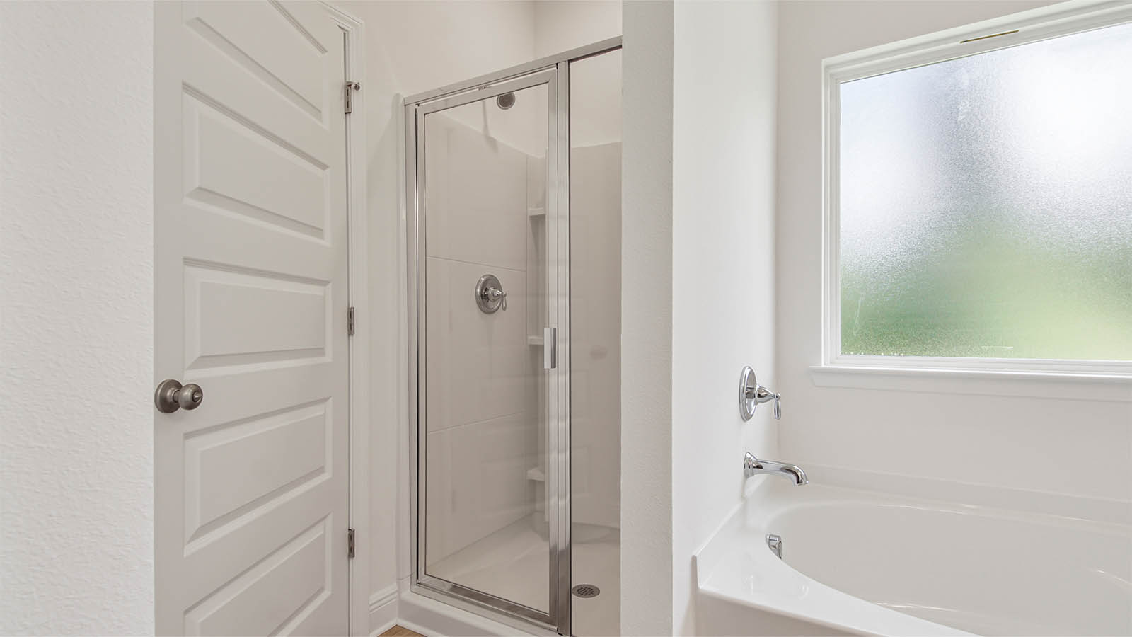 Primary bathroom with large soaking tub below a frosted glass window and a separate standing shower.