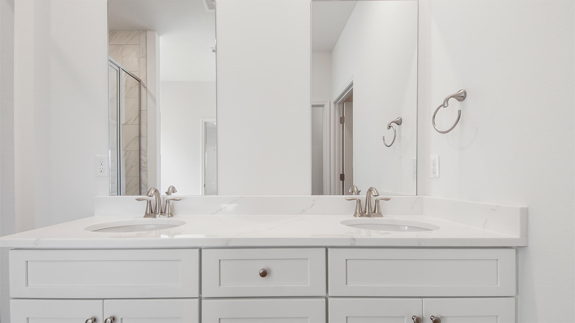 The primary bath has a dual sink vanity with quartz countertops and lower cabinetry and drawers for storage