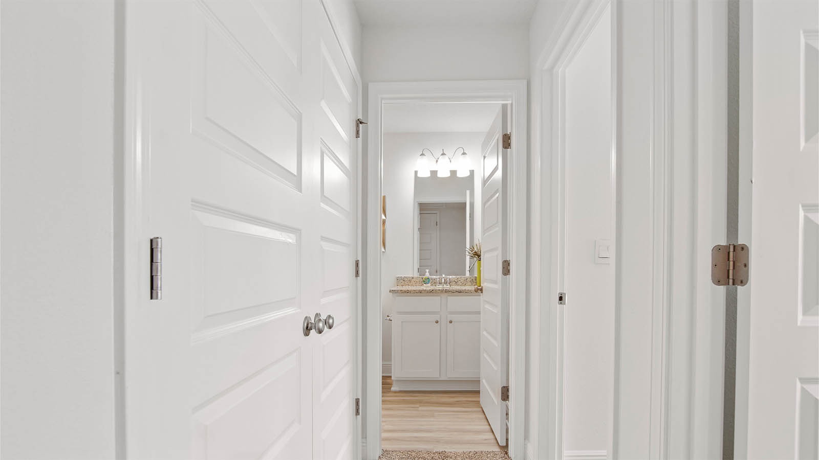 Hall leading to shared bathroom outside of additional bedrooms
