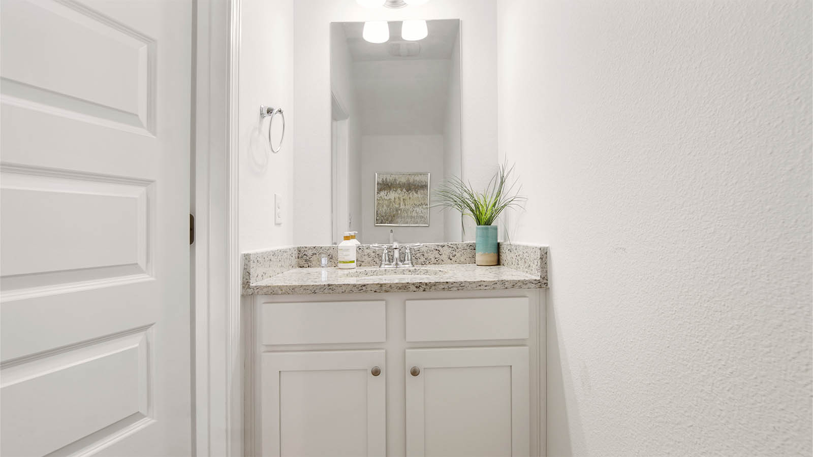 Main level half bath with single vanity featuring beautiful white cabinetry