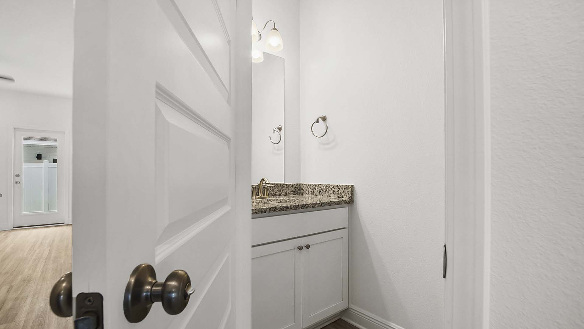The half bath off the entry hall has a single vanity with lower cabinetry for storage