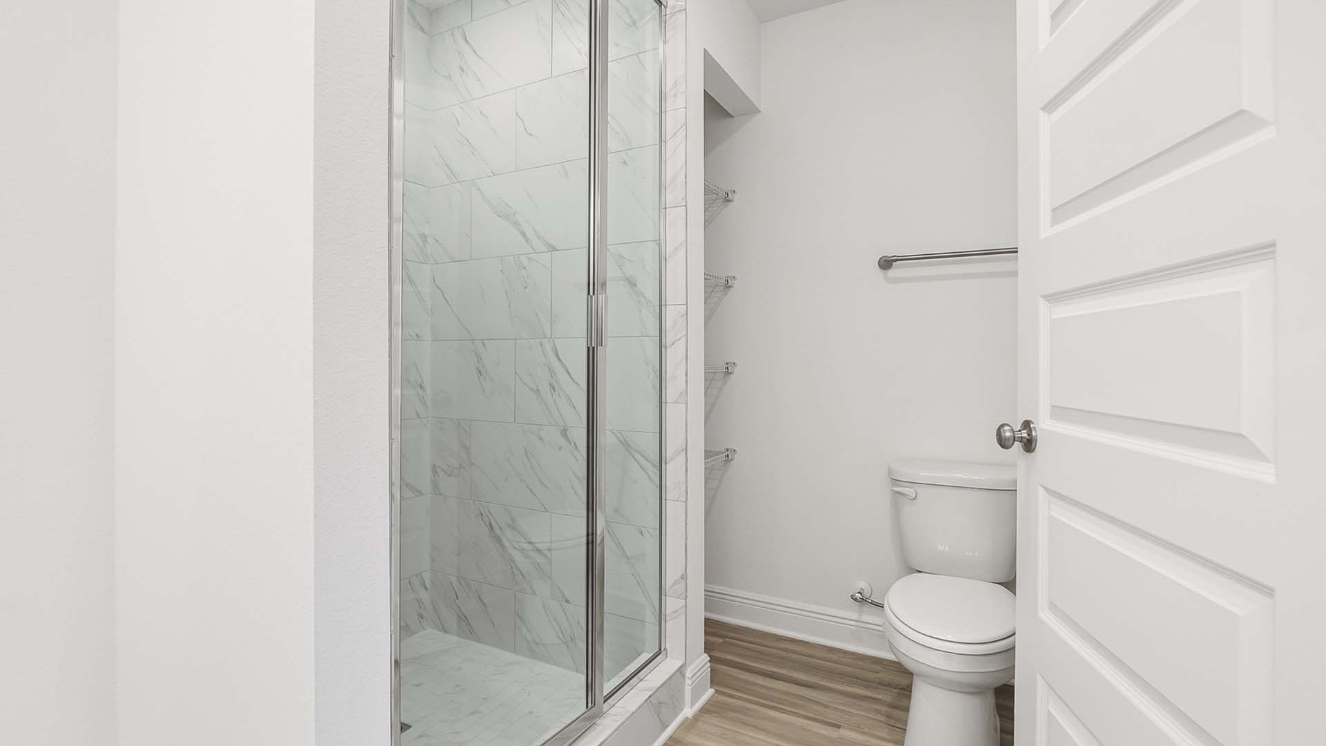 The shower in the primary bath has a glass enclosure and a linen storage area
