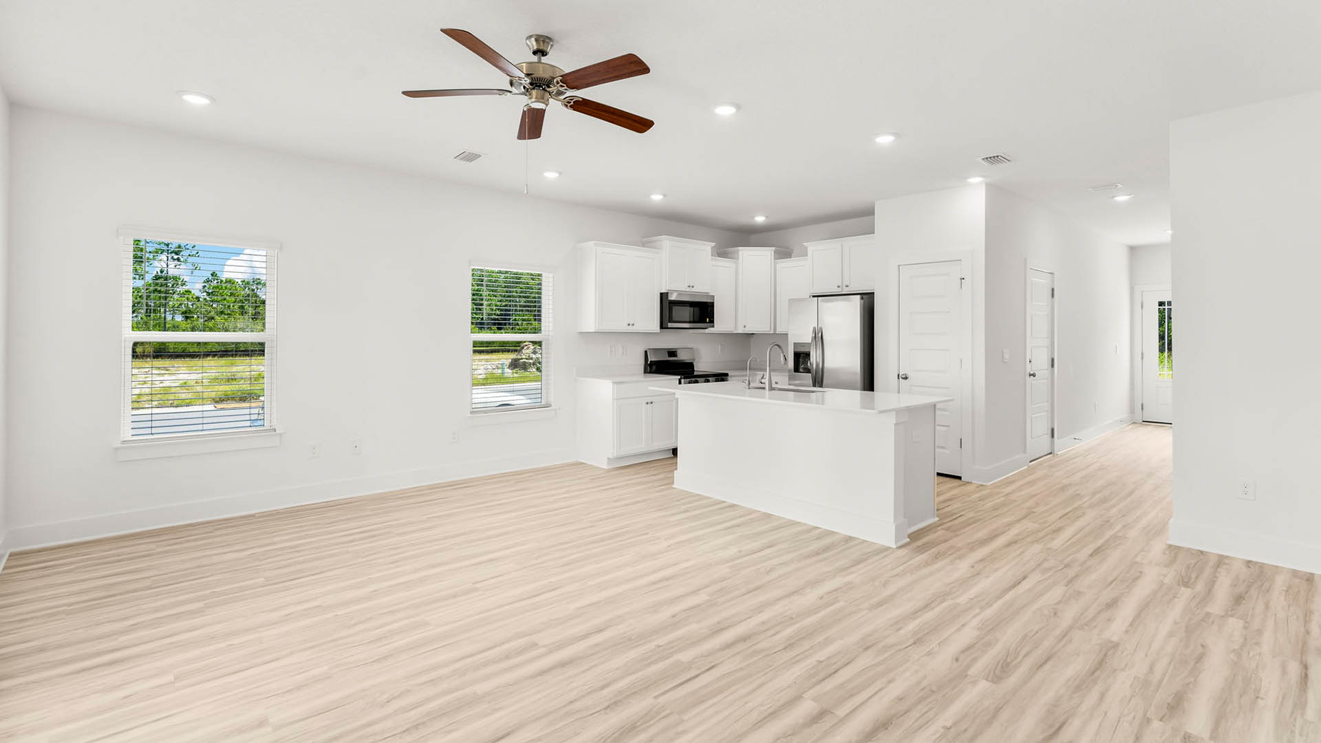 The spacious living area has an overhead fan and windows that flood this space with natural light