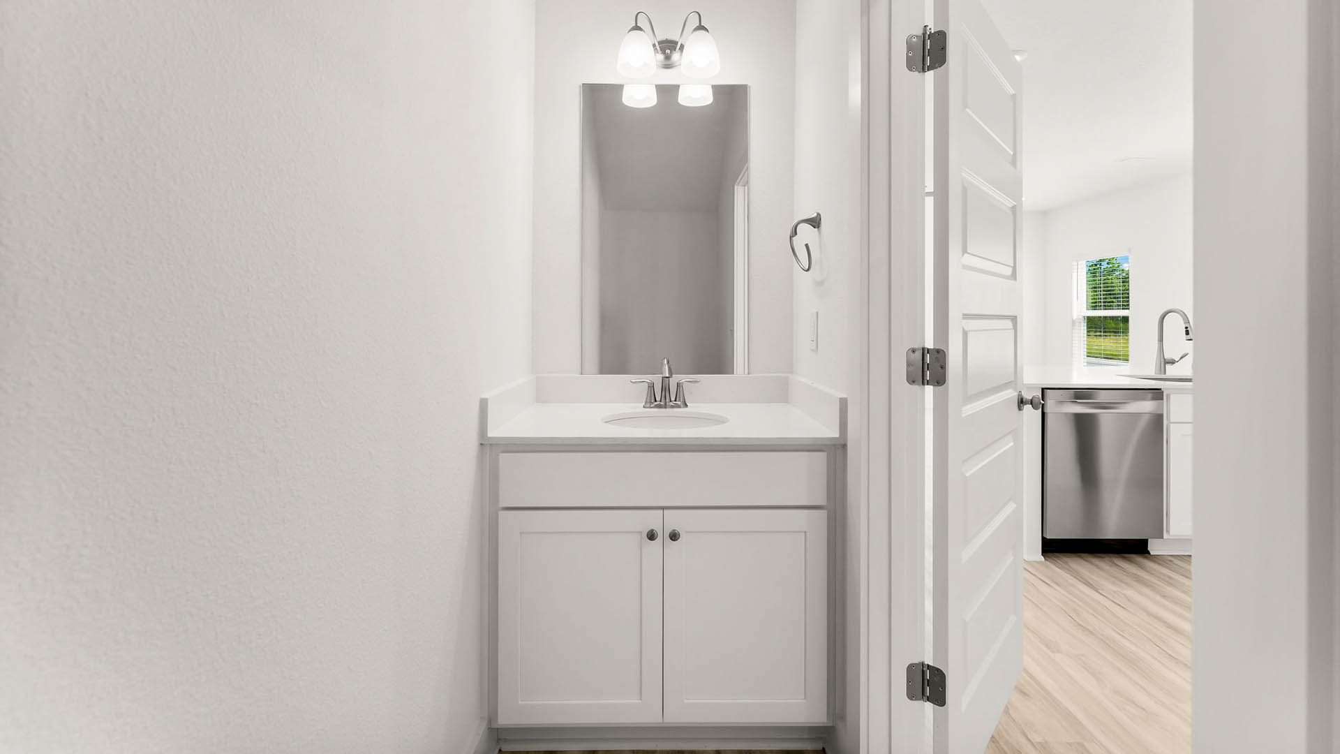 The half bath has single vanity with lower cabinetry for storage and quartz countertops