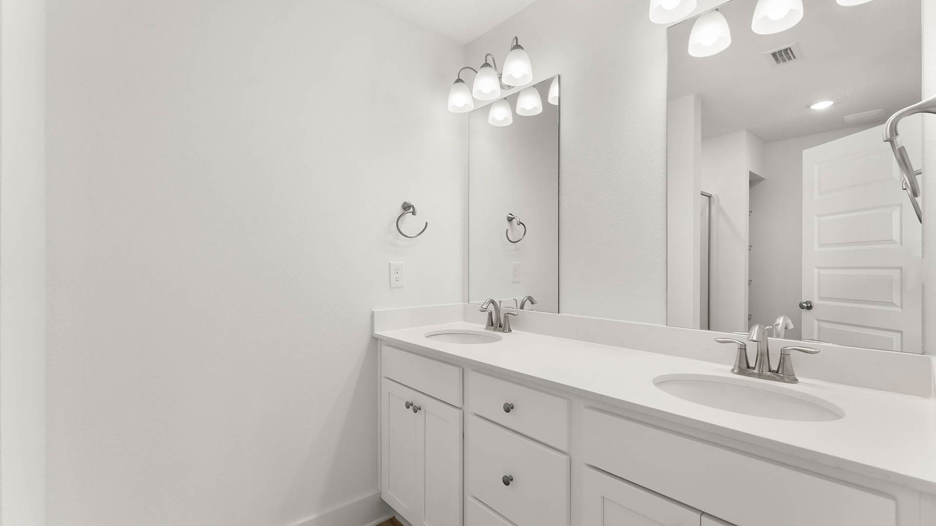 The vanity has quartz countertops and single glass vanity mirror over each sink