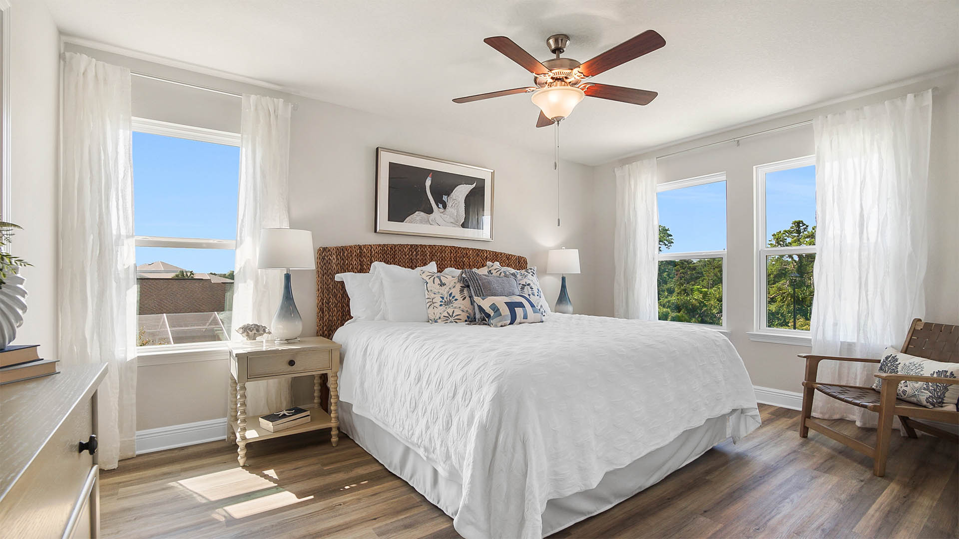 Primary bedroom with EVP flooring and ceiling fan and three windows.