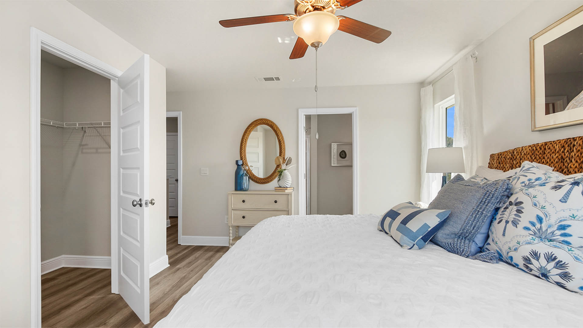 Primary bedroom with EVP flooring and ceiling fan and bathroom entrance and closet.