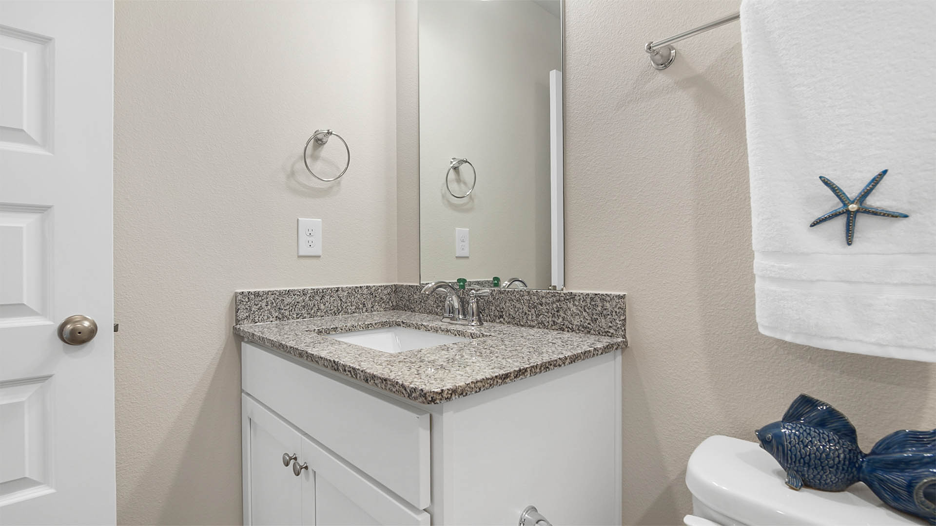 Bathroom with single vanity with granite countertops and white cabinetry.
