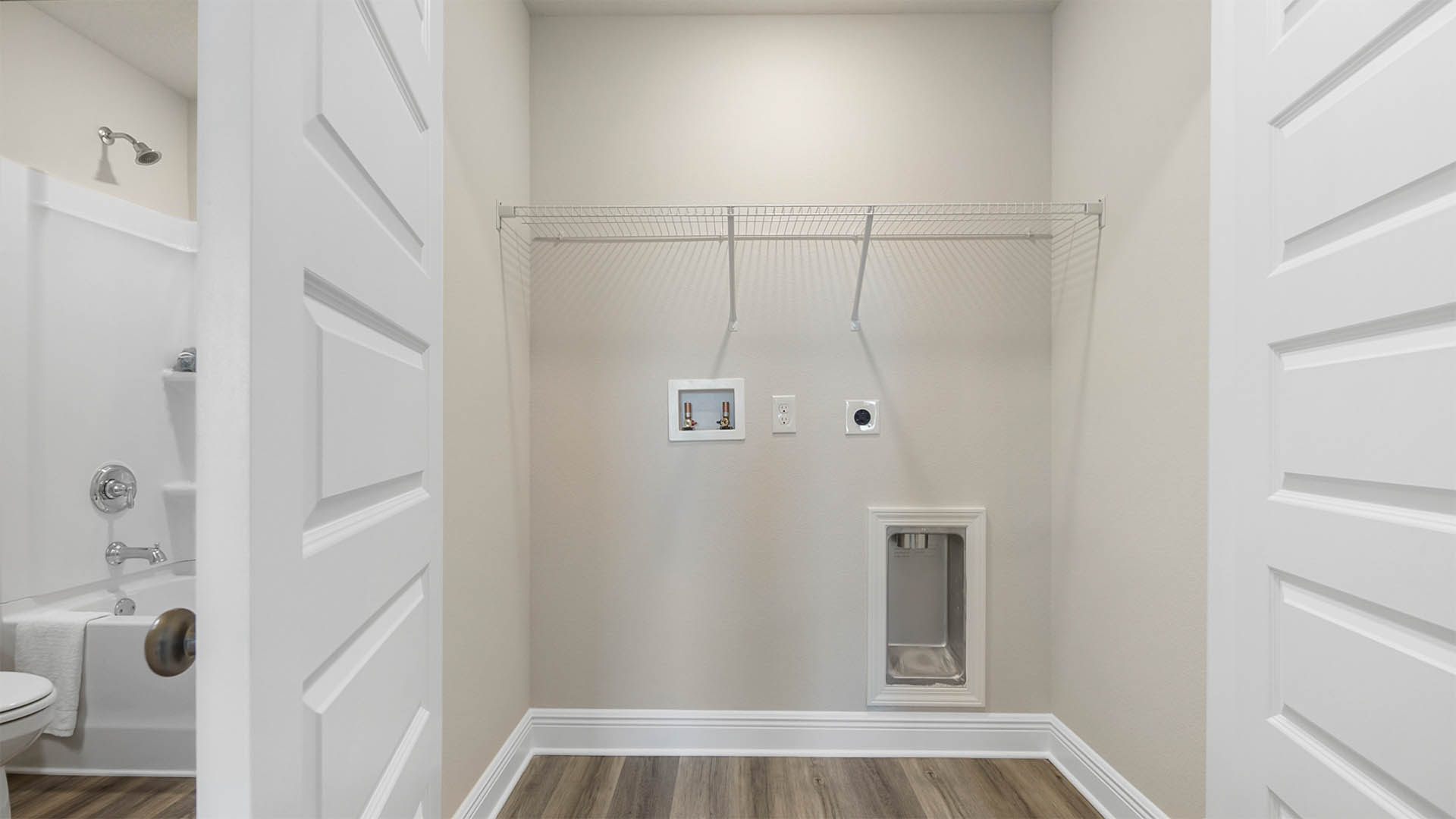 Laundry room in upstairs hallway next to guest bathroom with EVP flooring and ventilated shelving.