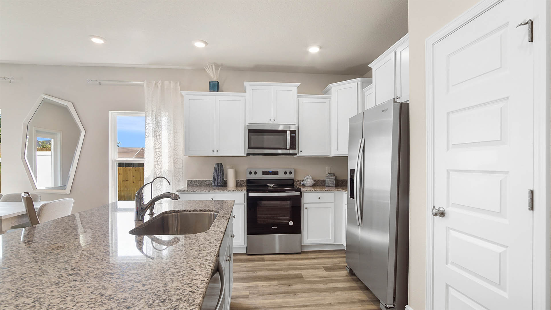 Open kitchen with island and granite countertops and stainless-steel appliances.
