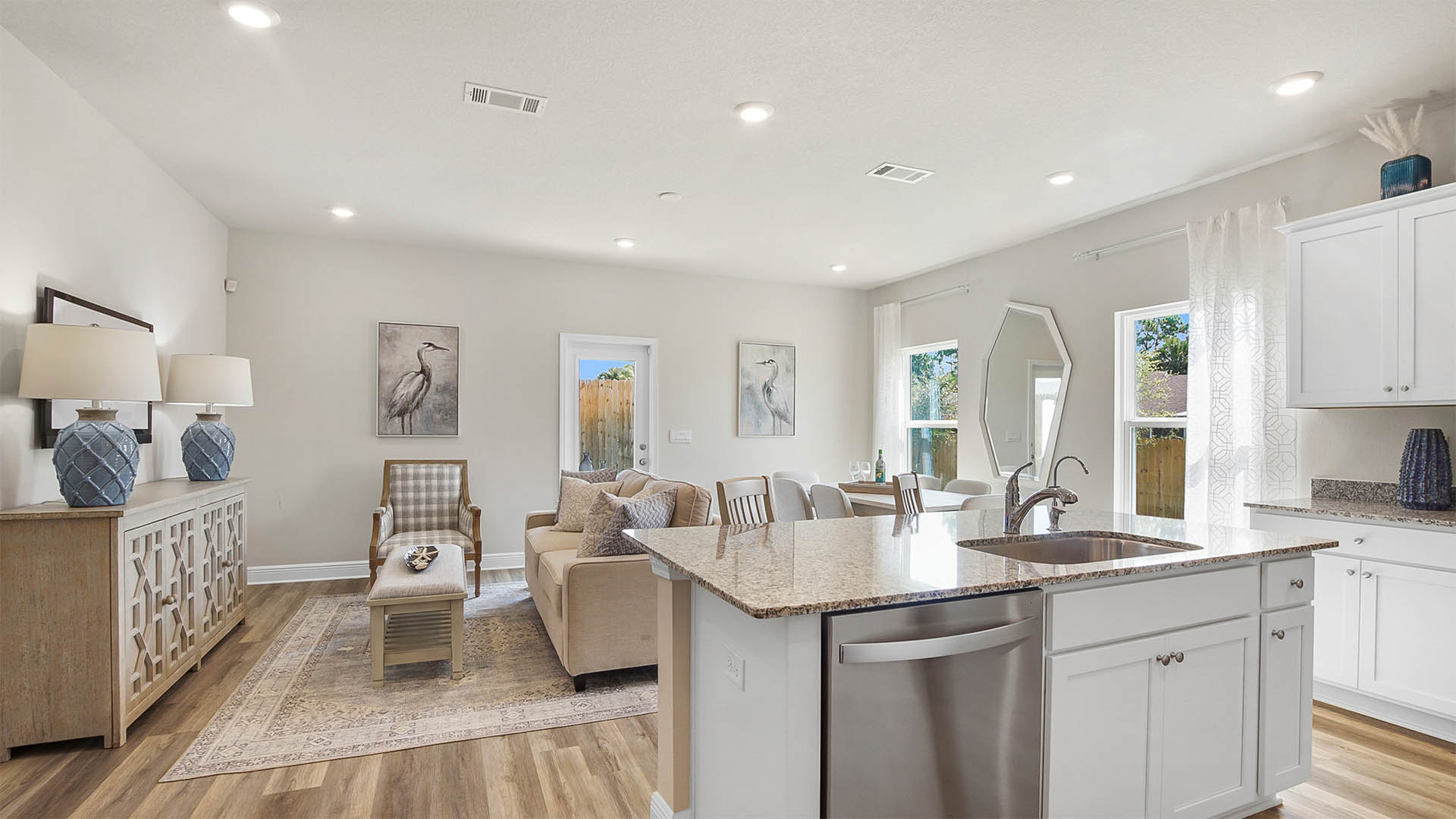 Open living room and kitchen and dining room with EVP flooring and glass back door.