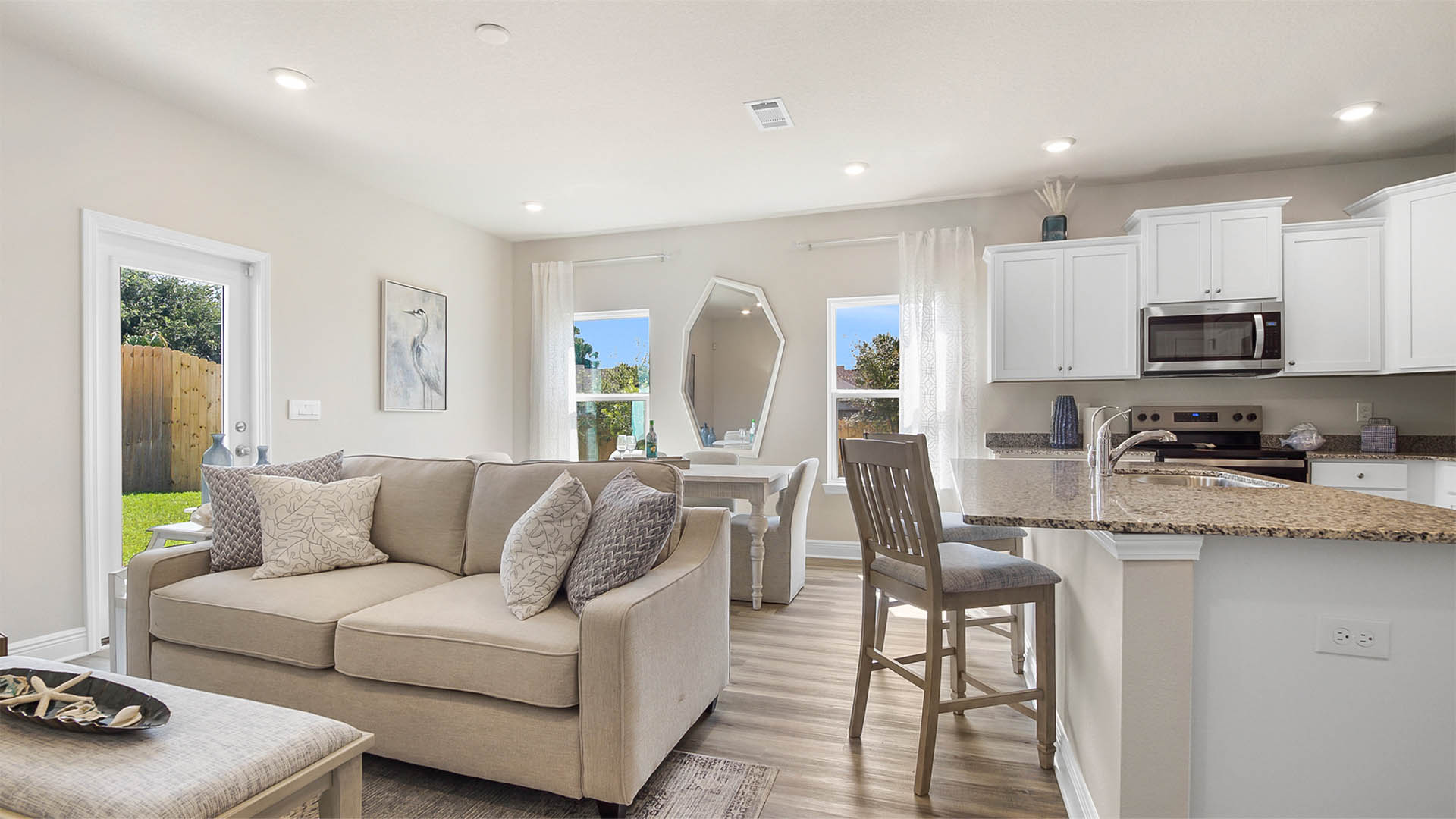 Open living area with living room and dining room and kitchen with two windows and glass back door.