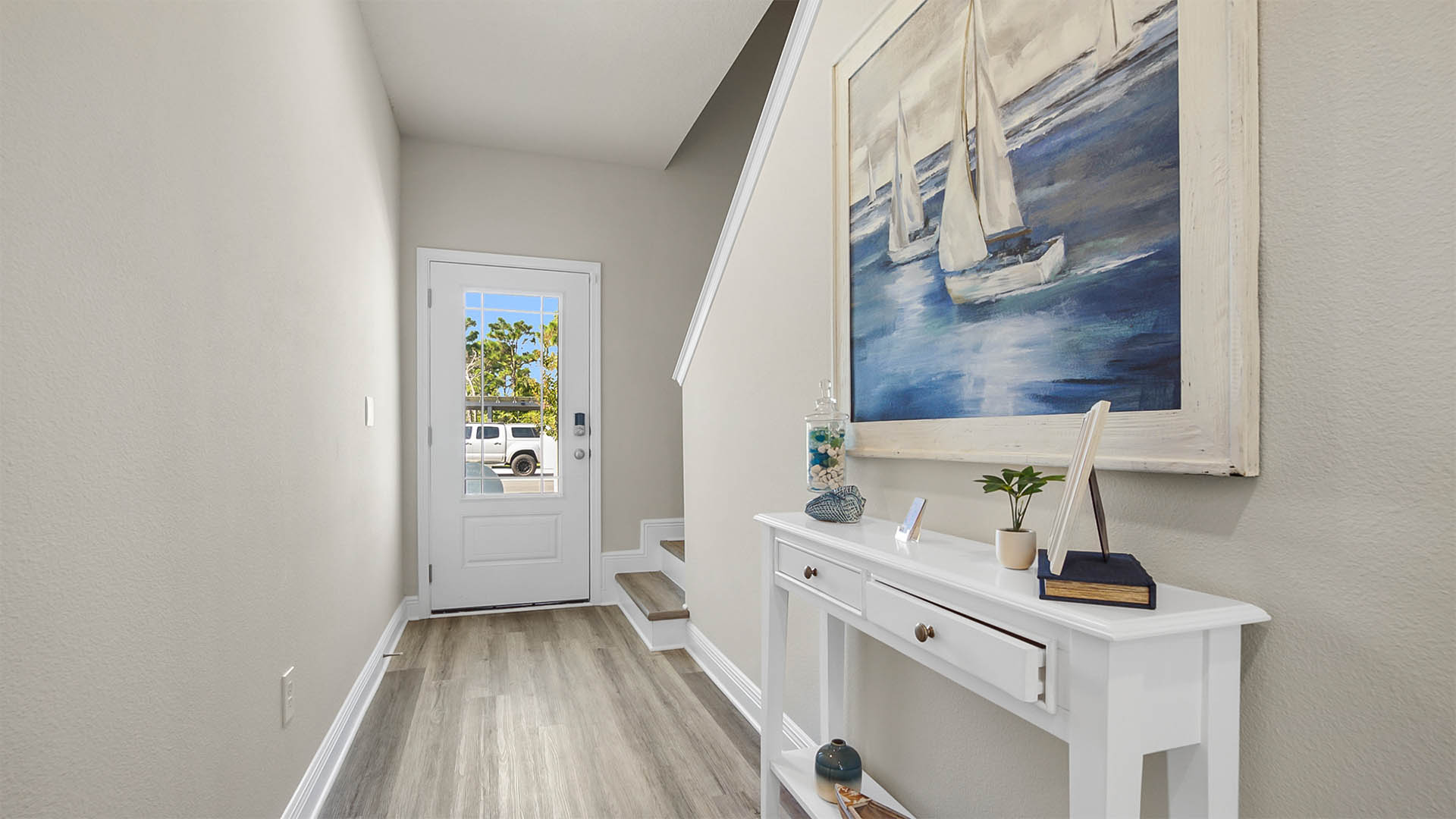 Hallway to stairway with EVP flooring next to front door with window.
