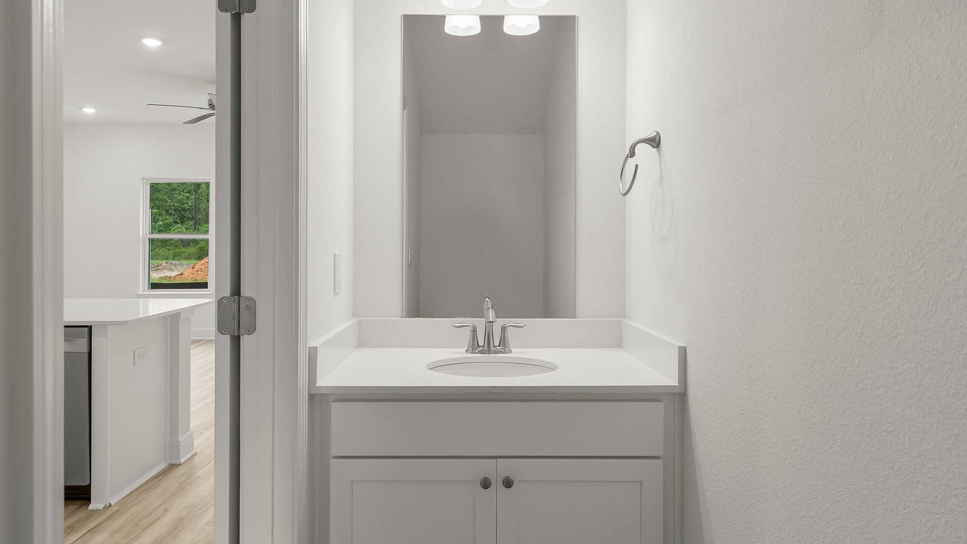 Half bath on the main level has a single vanity with lower cabinetry and quartz countertops