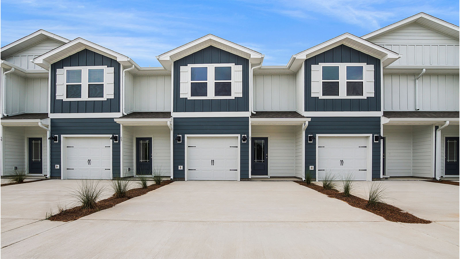 Two story townhomes interior units with 1 car garages and picture windows on second floor.