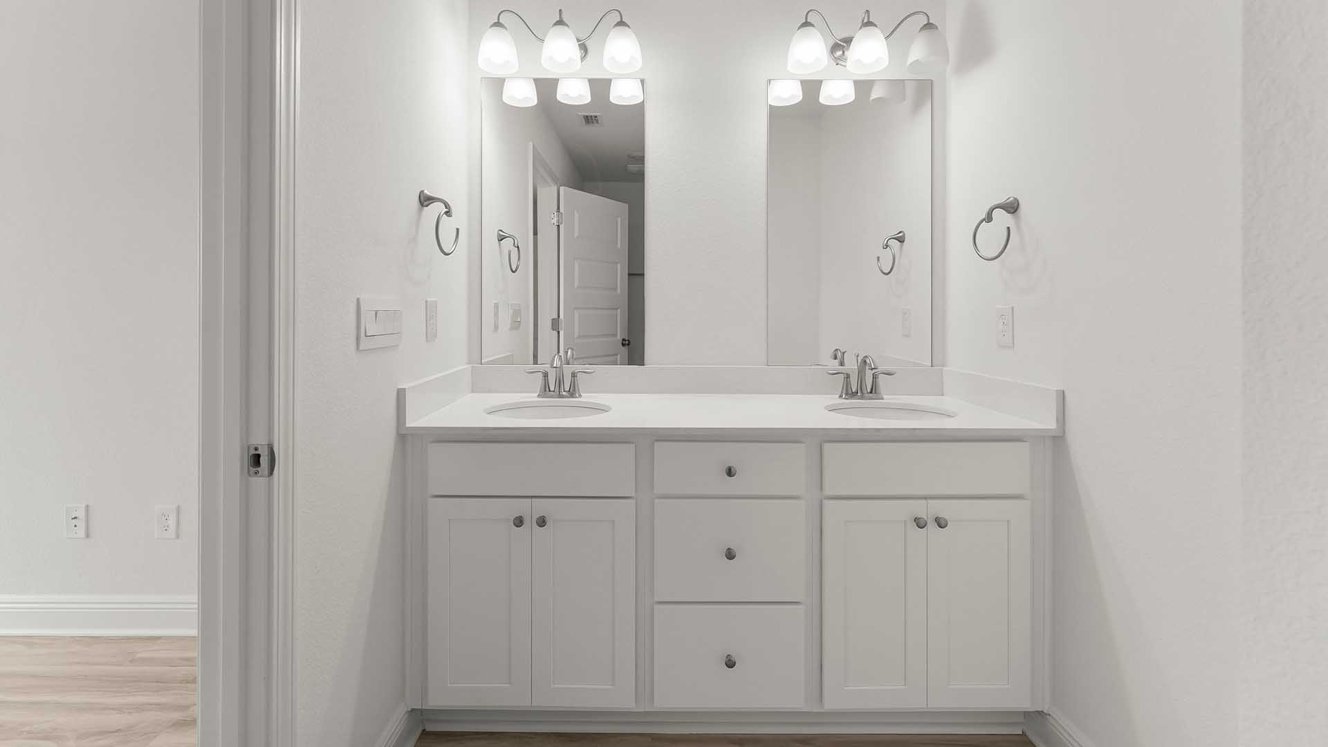 The dual sink vanity in the primary bathroom has lower cabinetry and drawers for storage and elegant quartz countertops