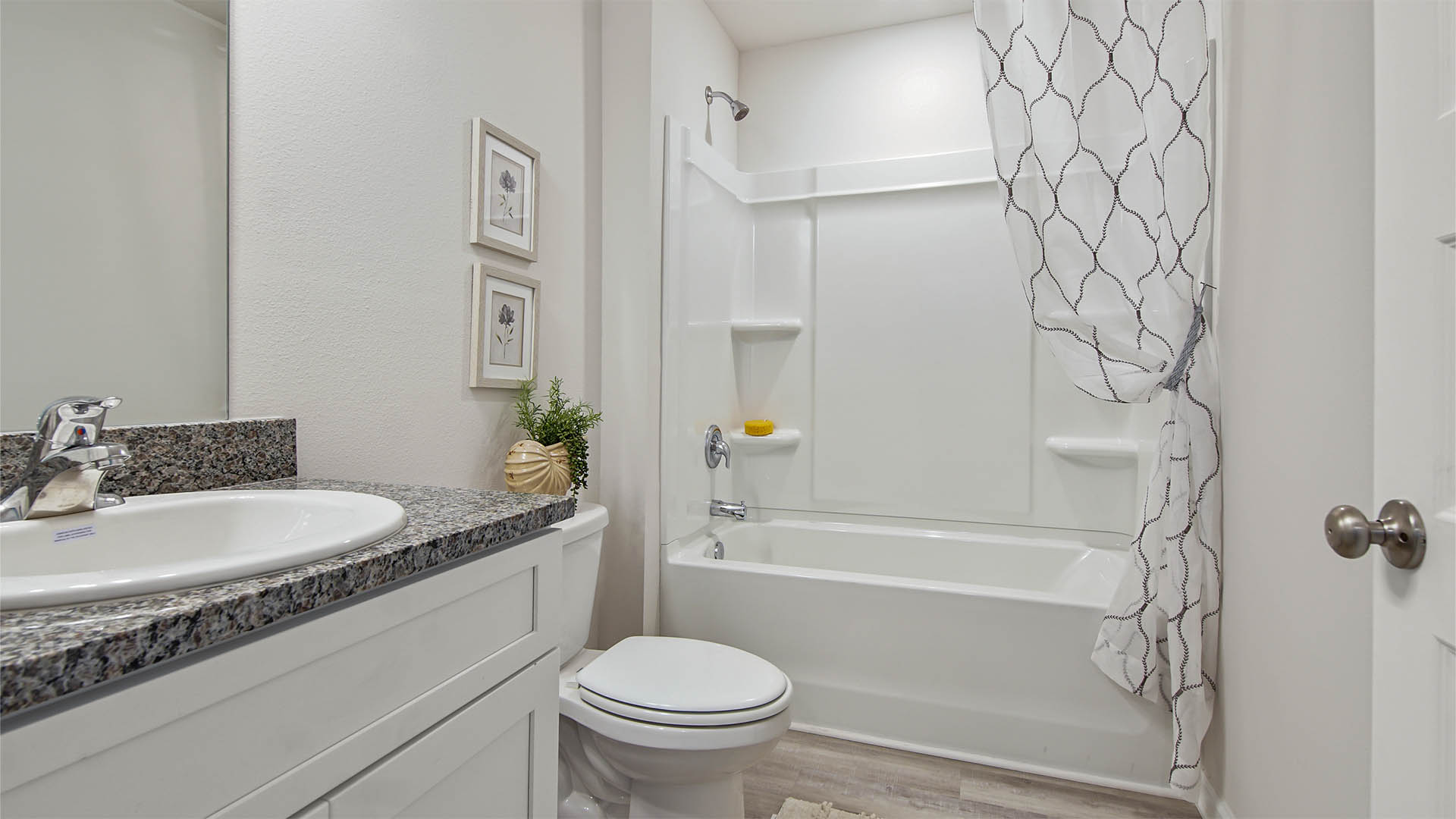 Shared bathroom between bedrooms two and three features granite countertop with vanity and lower cabinetry and shower tub combination