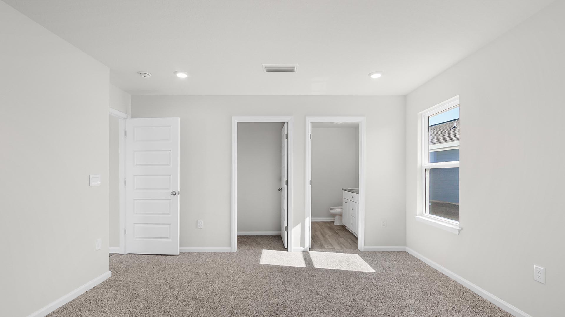 The primary bedroom is spacious and features plush carpet