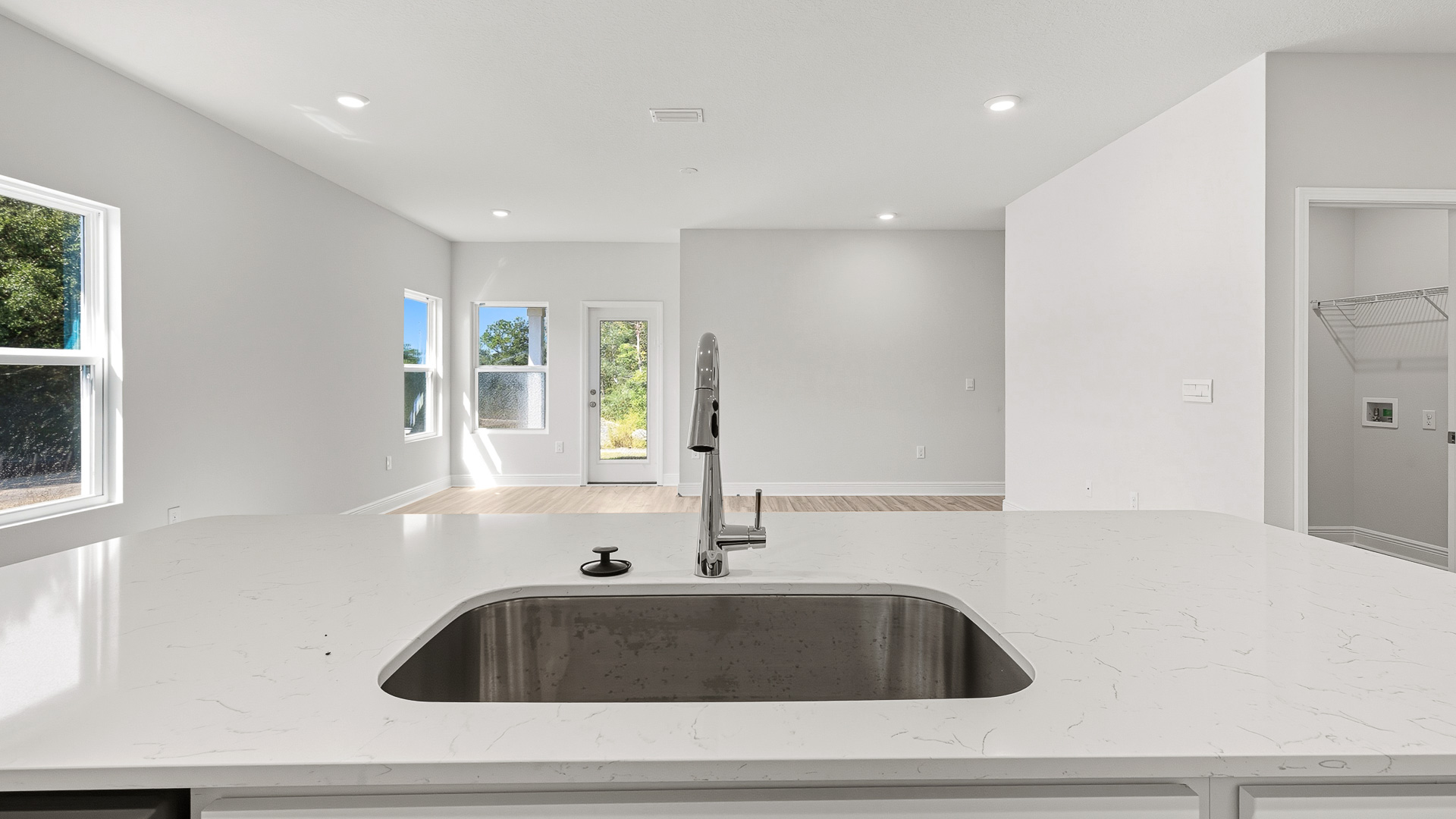 The kitchen island has a sink and dishwasher and looks out to the living room