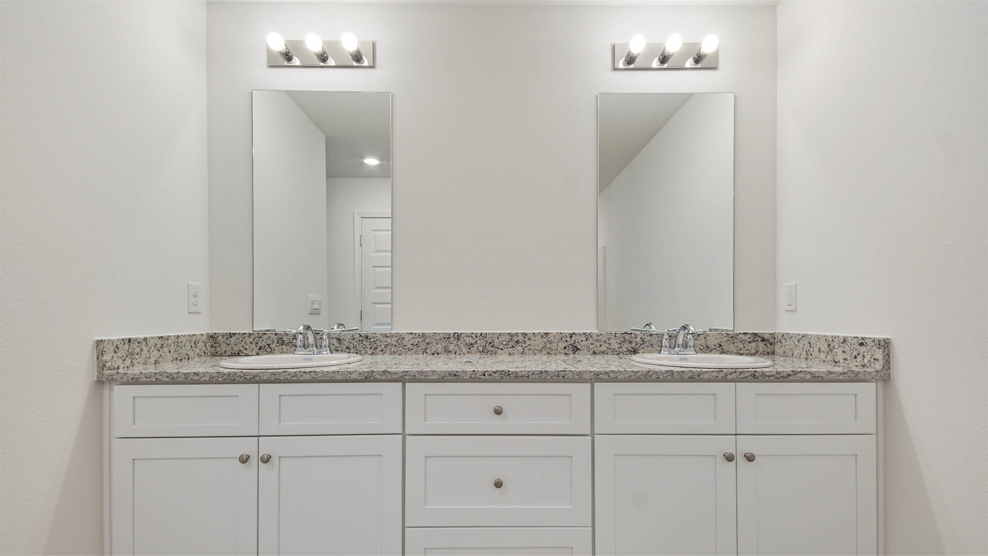 Primary bath with dual sink vanity and lower cabinetry and granite countertop