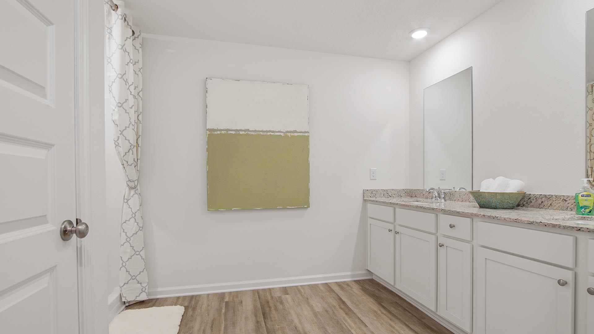 Primary bath with dual sink vanity and lower cabinetry and granite countertop