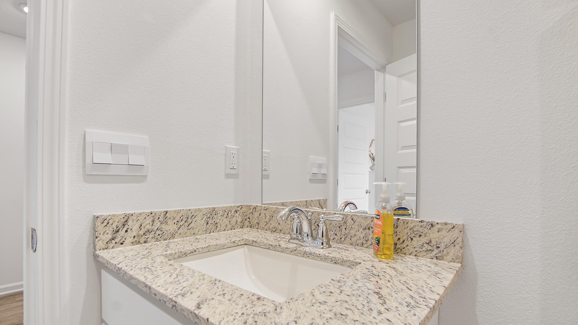 The shared bathroom is located off the foyer and it features granite countertops and a single vanity and lower cabinetry