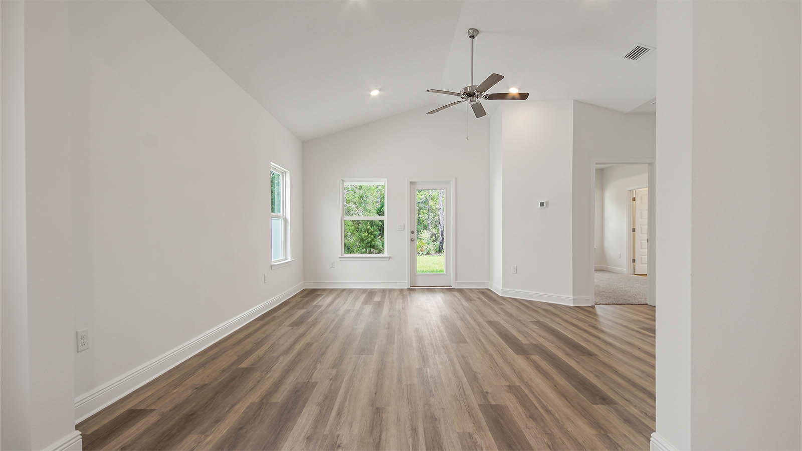 Bright open living area with kitchen and dining room flowing into living room with multiple windows and EVP flooring.