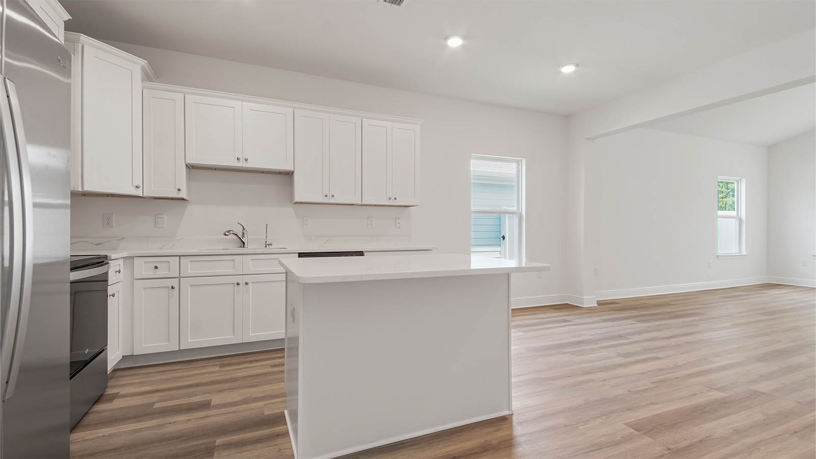 Open concept kitchen and living area with EVP flooring and quartz countertops and EVP flooring and a kitchen island.