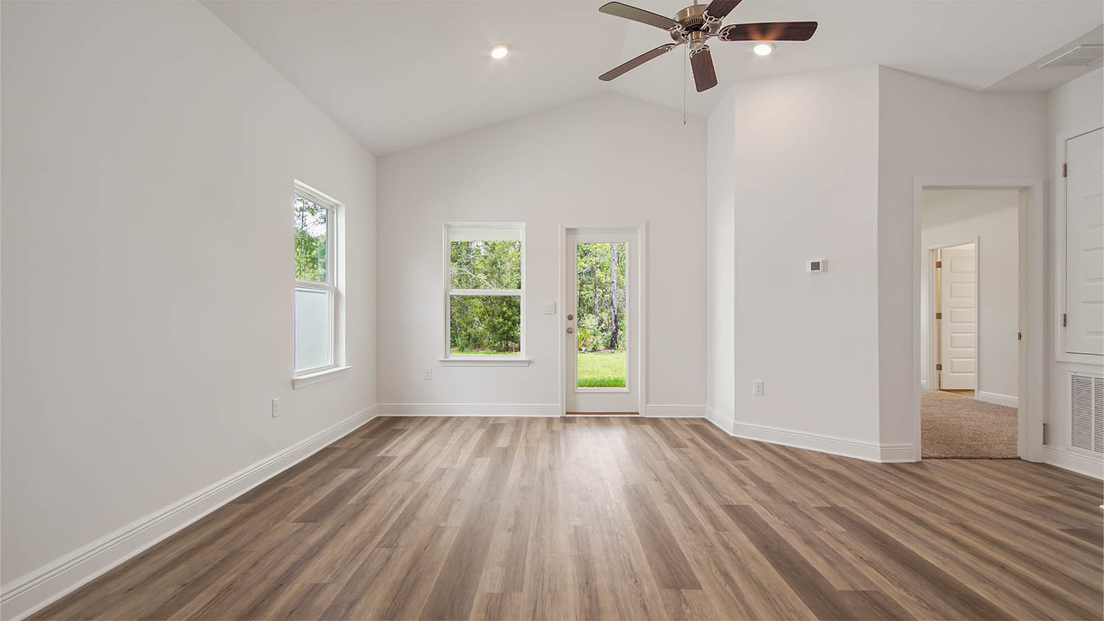 Living room with vaulted ceilings and window and glass back door to covered back patio.