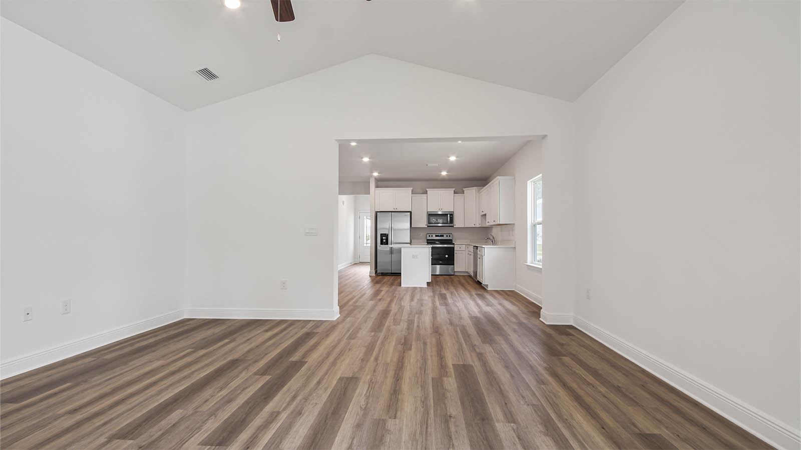 Living room with EVP flooring and a ceiling fan and door to primary bedroom.