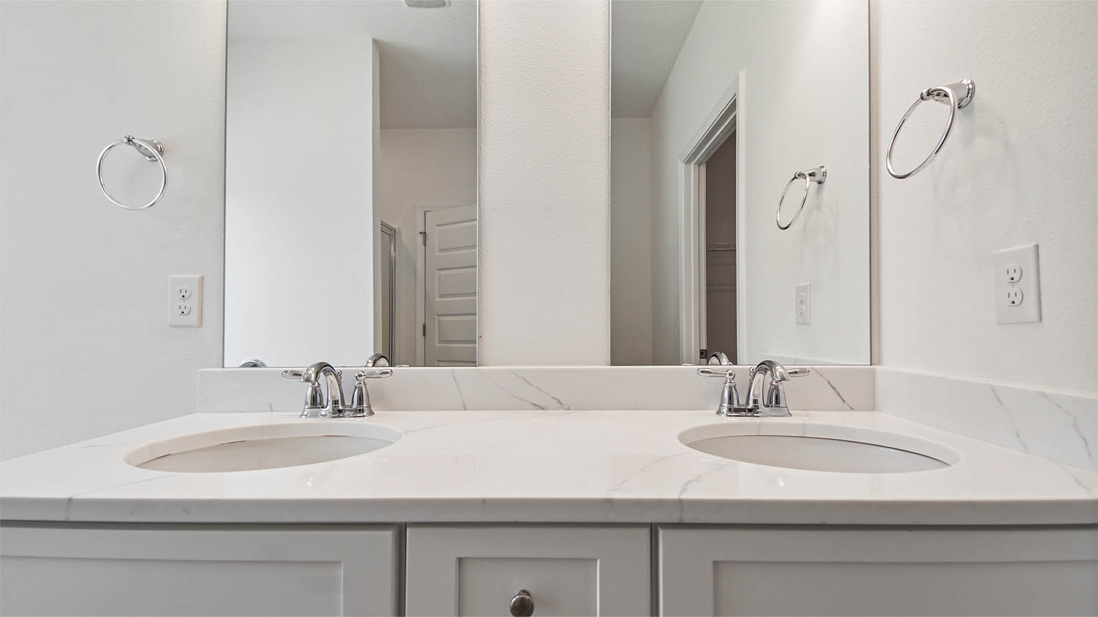 Primary bathroom with a double vanity with quartz countertops and white cabinetry.