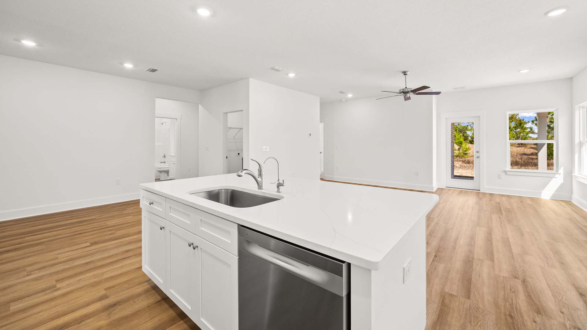 The center island has quartz countertops and lower cabinetry. It holds the sink and dishwasher for easy meal service and cleanup