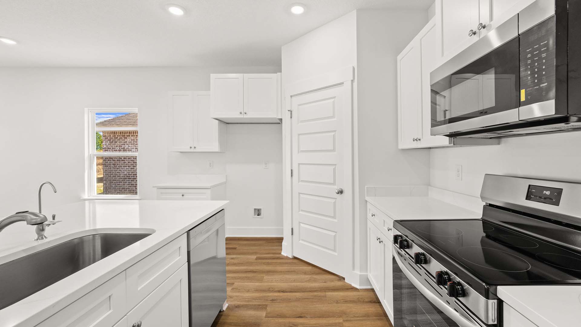 The kitchen has a stove and microwave as well as upper and lower cabinetry for storage