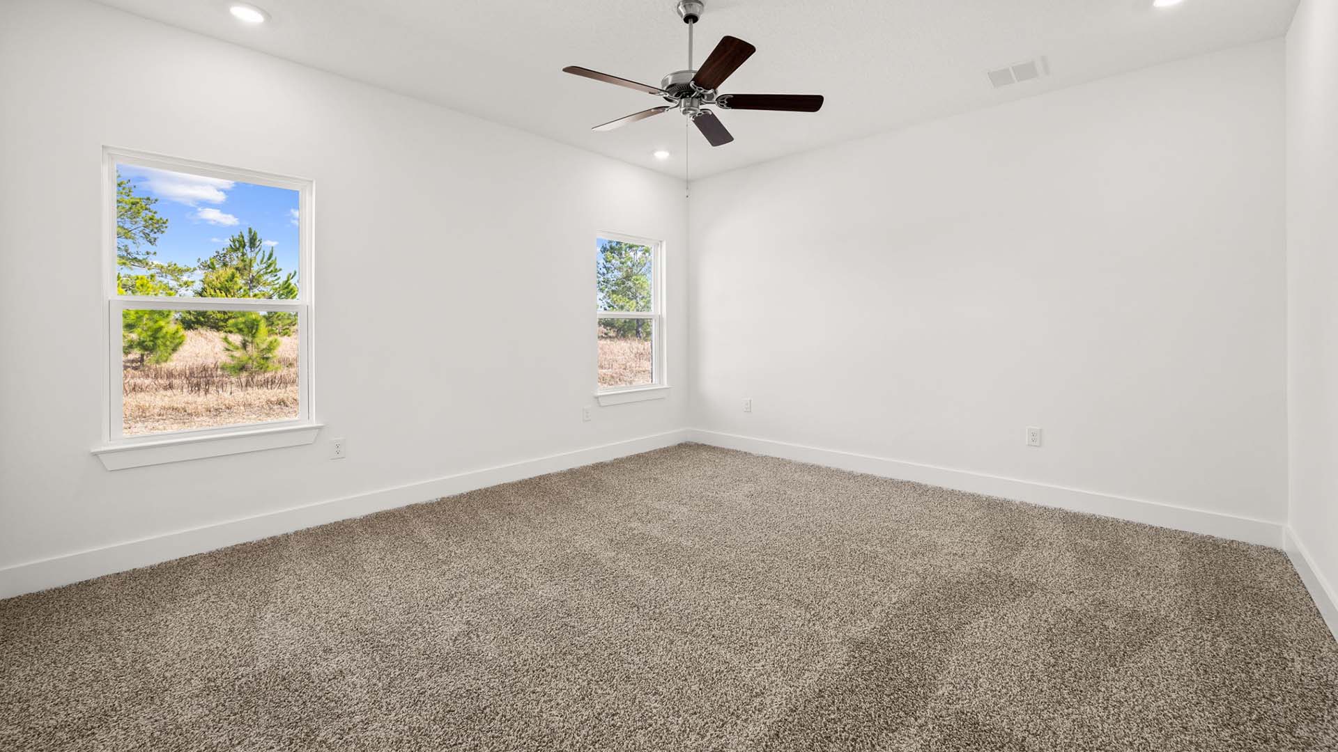 The primary bedroom has a ceiling fan and windows for natural light