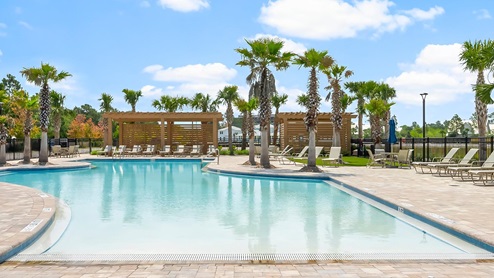 Resort style pool with zero entry as well as a cabana and outdoor kitchen area