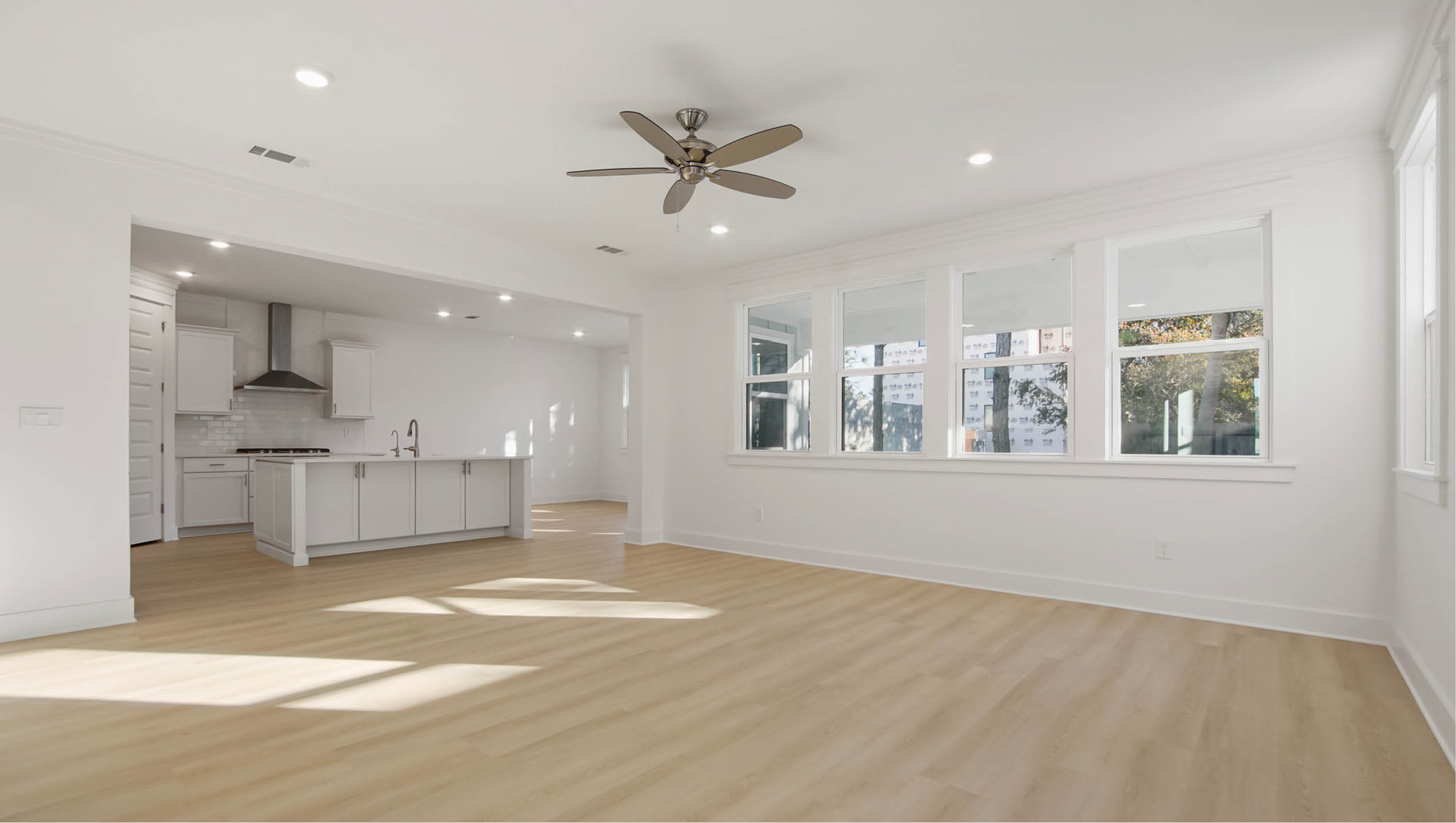 Great room open to kitchen with wood flooring and ceiling fan