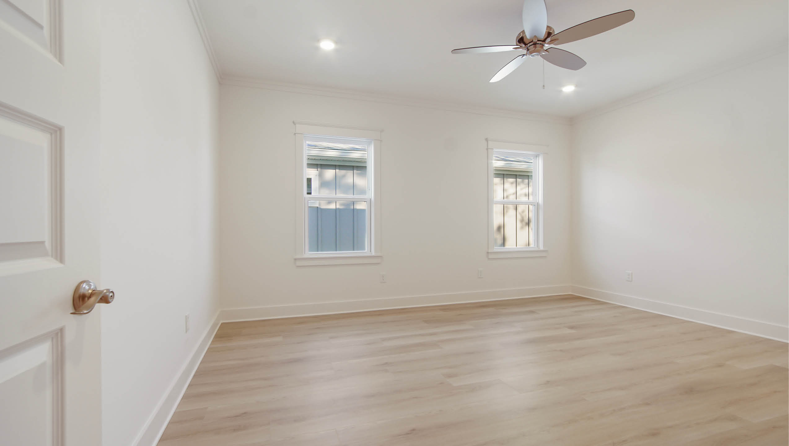 Primary bedroom with wood flooring and ceiling fan