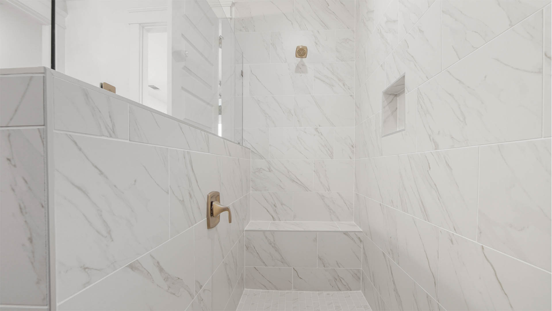 Primary bathroom shower with tile and bench