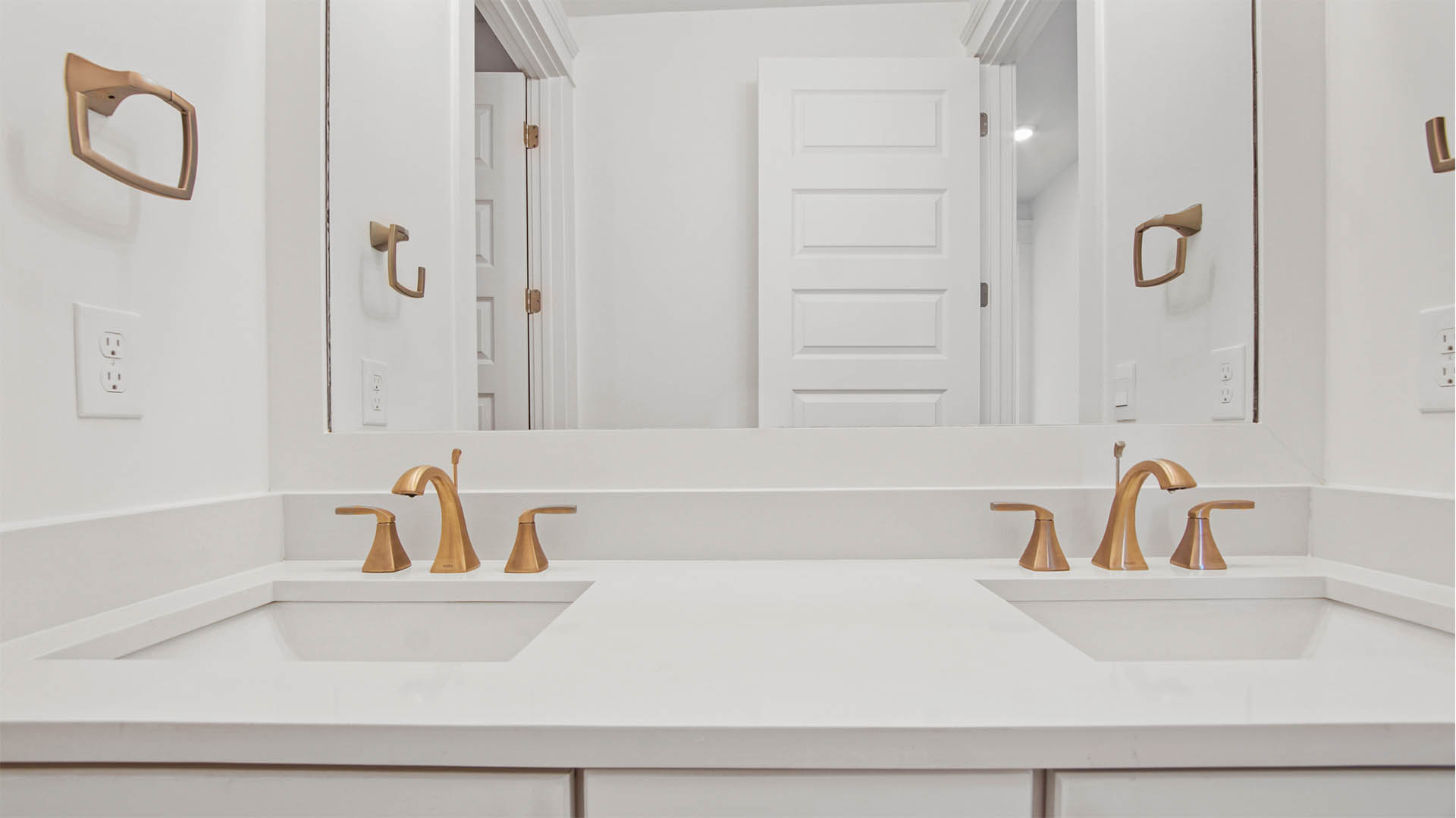 Shared bathroom with dual sink vanity with quartz countertop and elegant fixtures