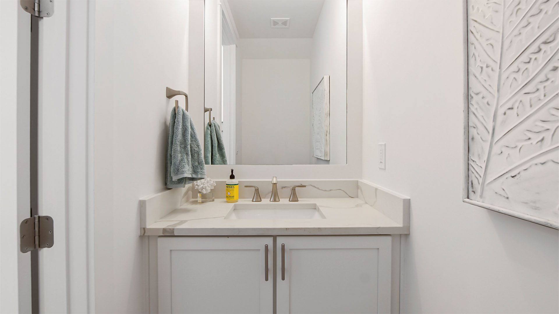 Powder room with single vanity with quartz countertops and white cabinetry