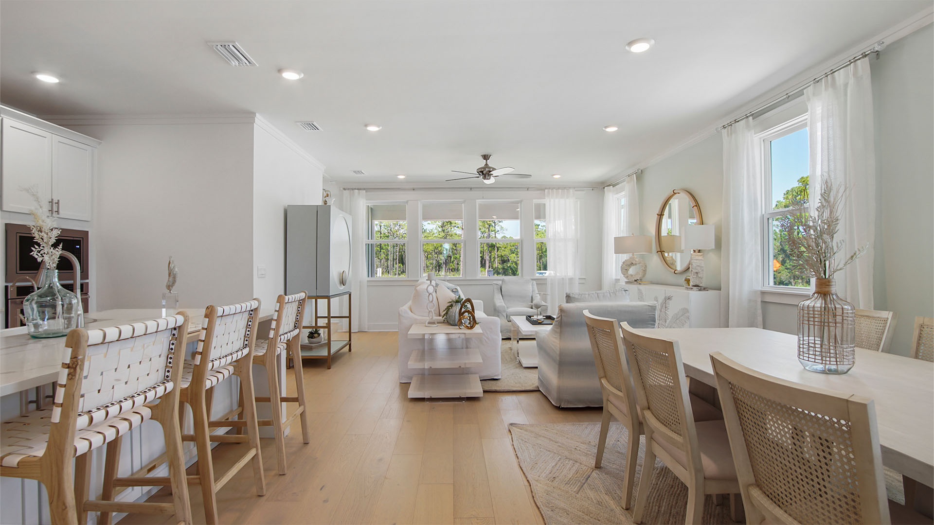 Opening living area with large kitchen island with bar seating and wood flooring and dining with window next to living area.