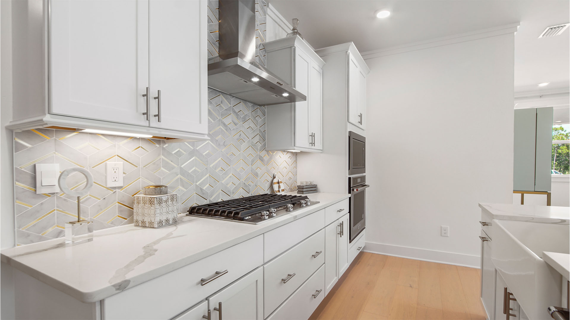Kitchen with gas stove top and stainless-steel vent hood.