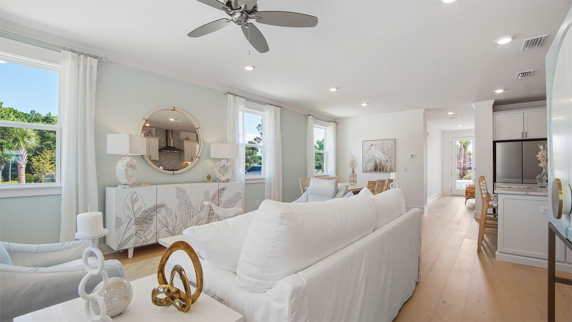 Living room with wood flooring next to kitchen and hallway for foyer.