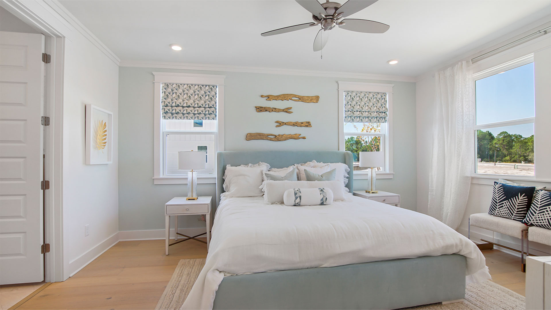 Primary bedroom with wood flooring and 3 windows and ceiling fan.