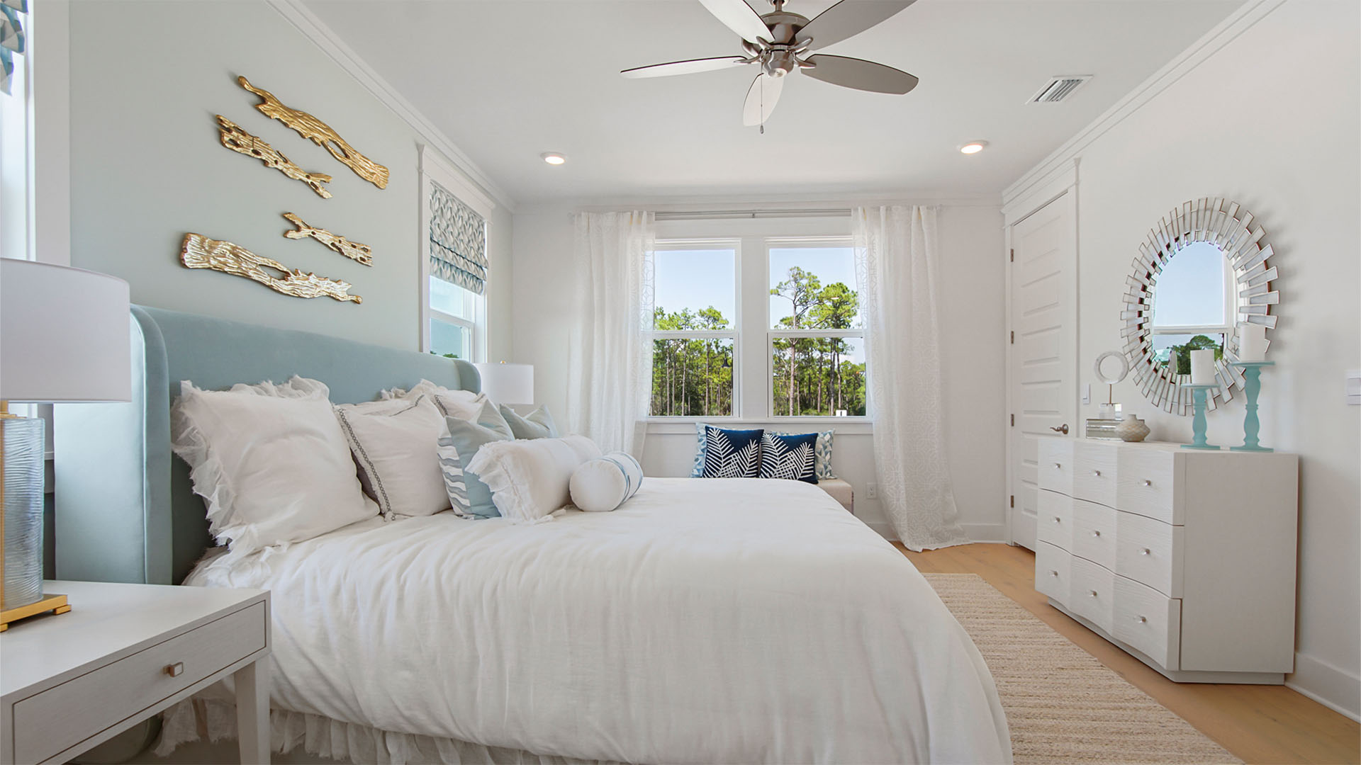 Primary bedroom with wood flooring and large windows and ceiling fan.