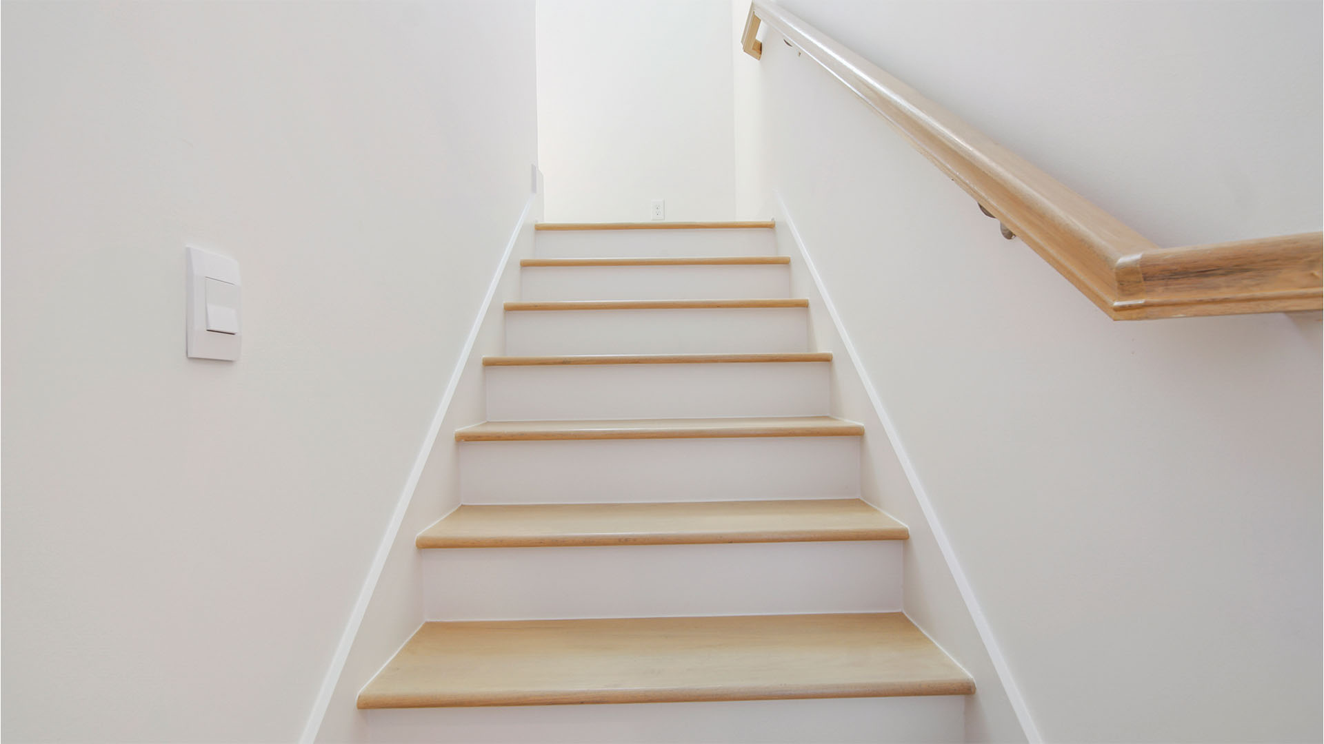 Stairs to second floor with wood treads and wooden handrail.