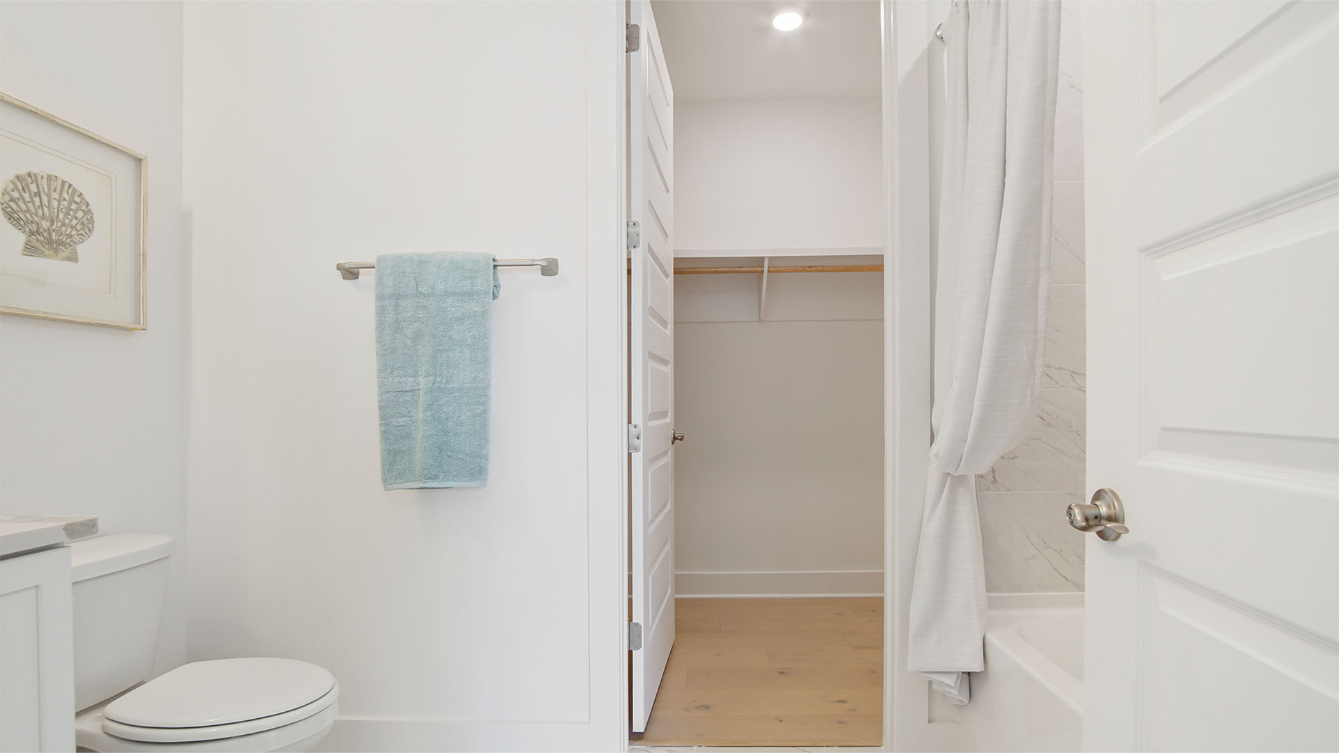Full bathroom off of bedroom two with tile flooring and walk-in closet with wood flooring.